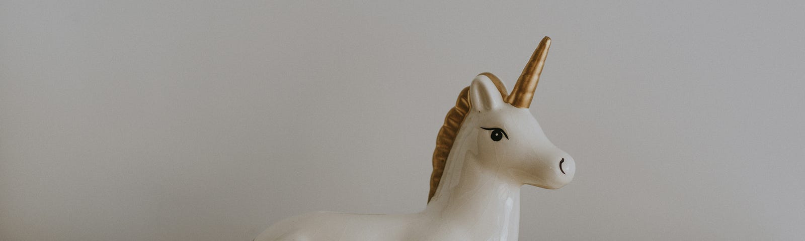 A porceilin unicorn sitting in front of piles of cents.