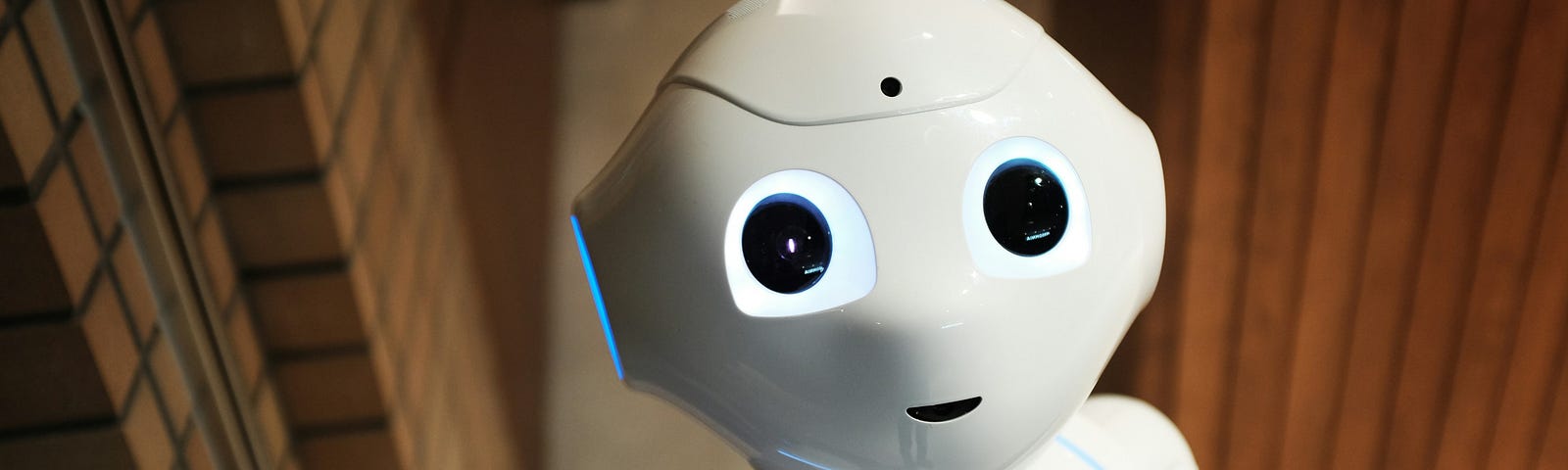 An adorable, friendly-looking, smooth plastic robot smiles up at camera.