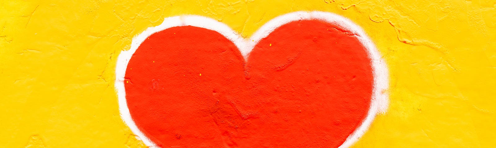 Painting of a red heart with a white outline on a yellow wall.