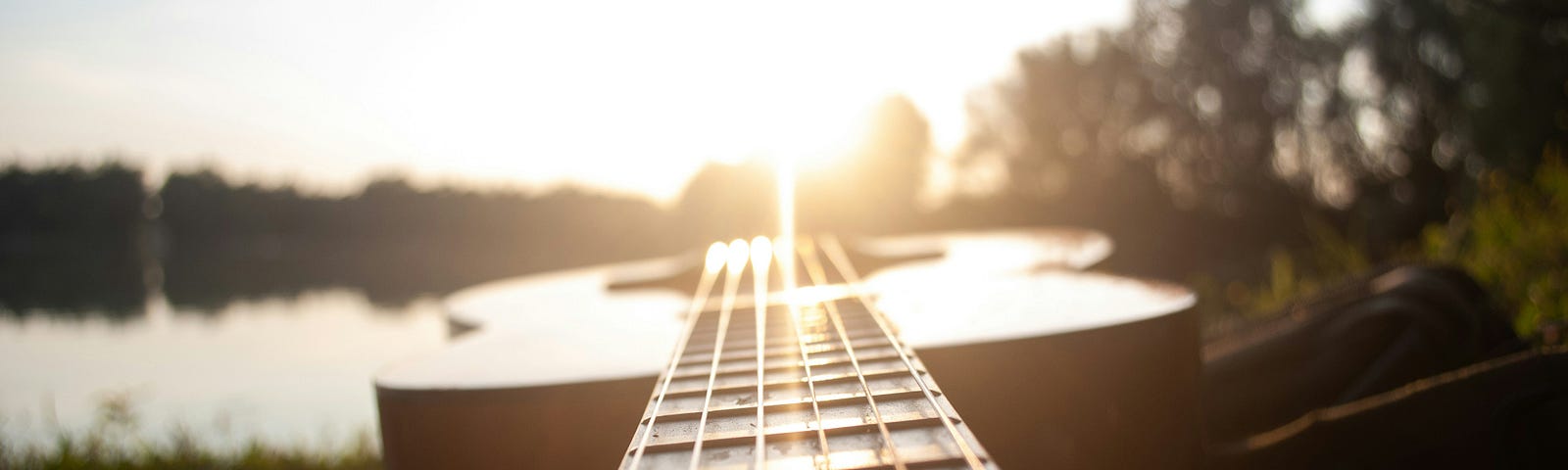 An acoustic guitar lays flat while the suns rays illuminates its strings