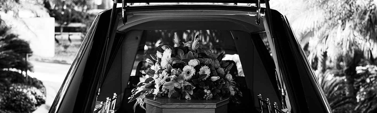 The rear of a hearse holding a coffin covered in flowers.