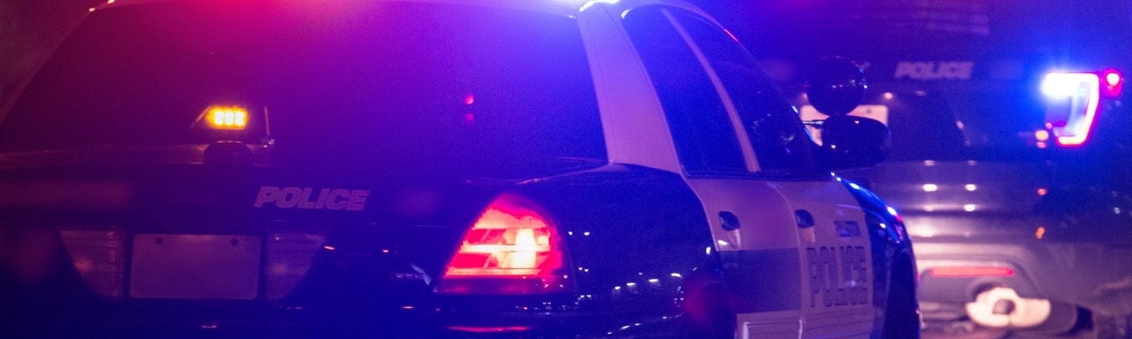 Police cars at night with roof lights on. Photo by MattGush/Getty Images