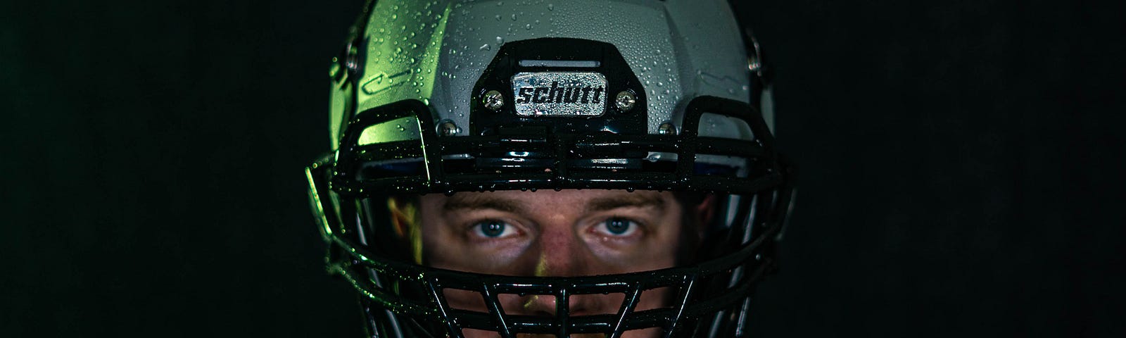 A man wearing a football helmet, gazing straight at the camera