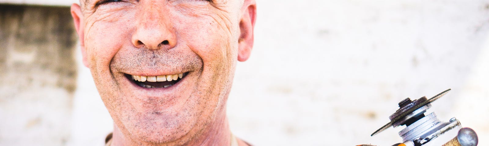 A smiling man holding a tool