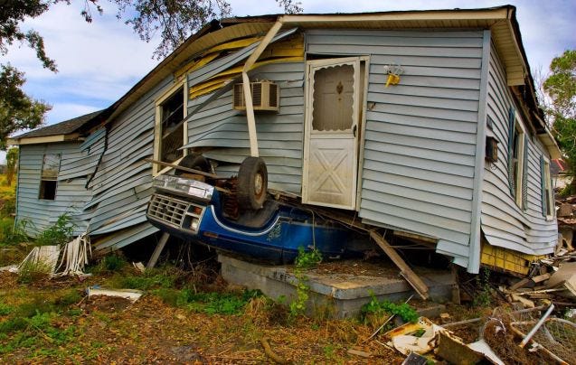 House knocked off foundation and laying on top of an upside down pickup truck after hurricane in Louisiana.