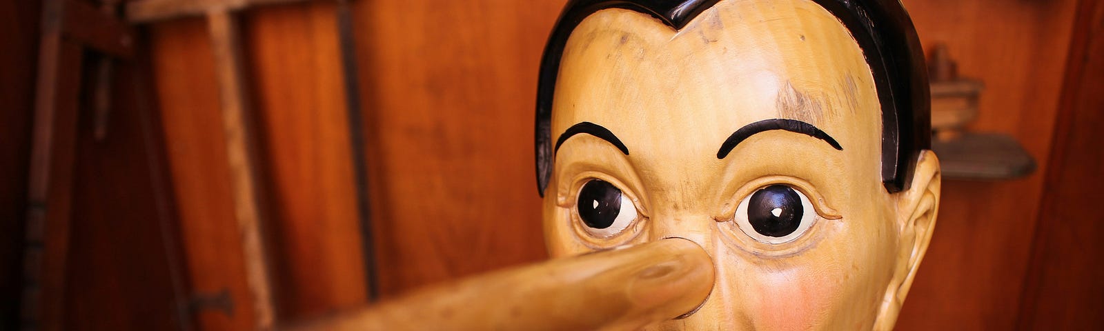 an old-fashioned wooden face of a child resembling Pinocchio with a long exaggerated nose