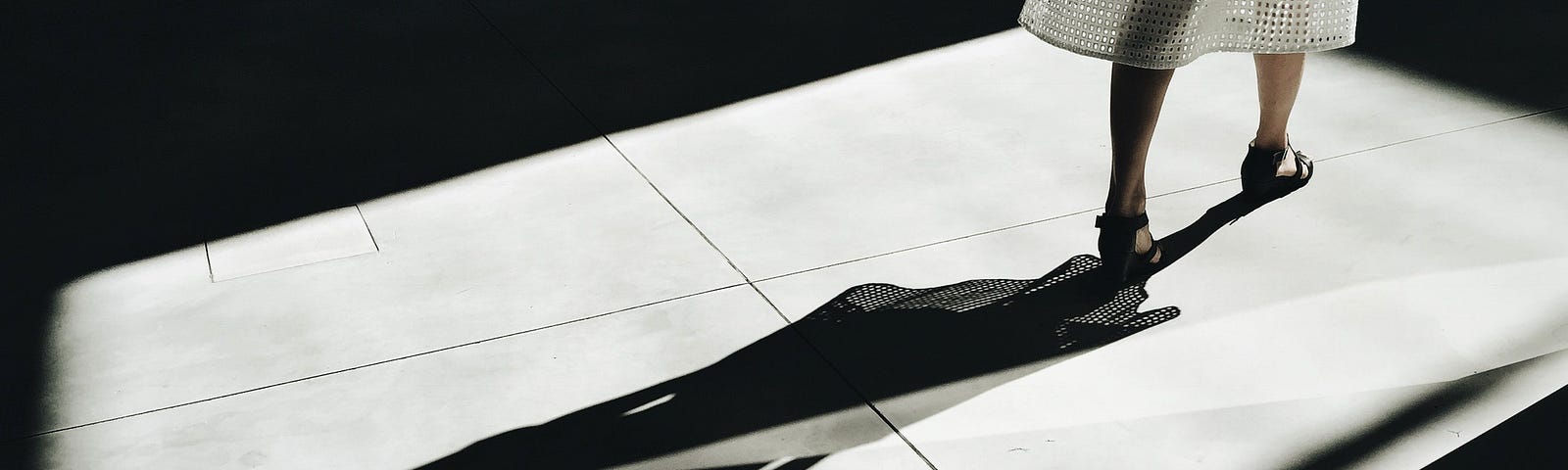 A lady standing and her shadow on the floor is seen