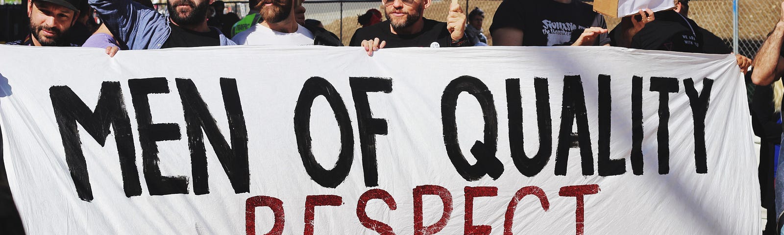 photo of men holding a banner in support of womens equality in article by Sav May about the ERA and Michele Thorne’s activism