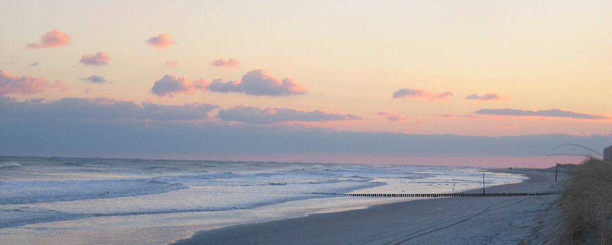 Brigantine Beach at sunset with waves and a variety of tracks in the sand.