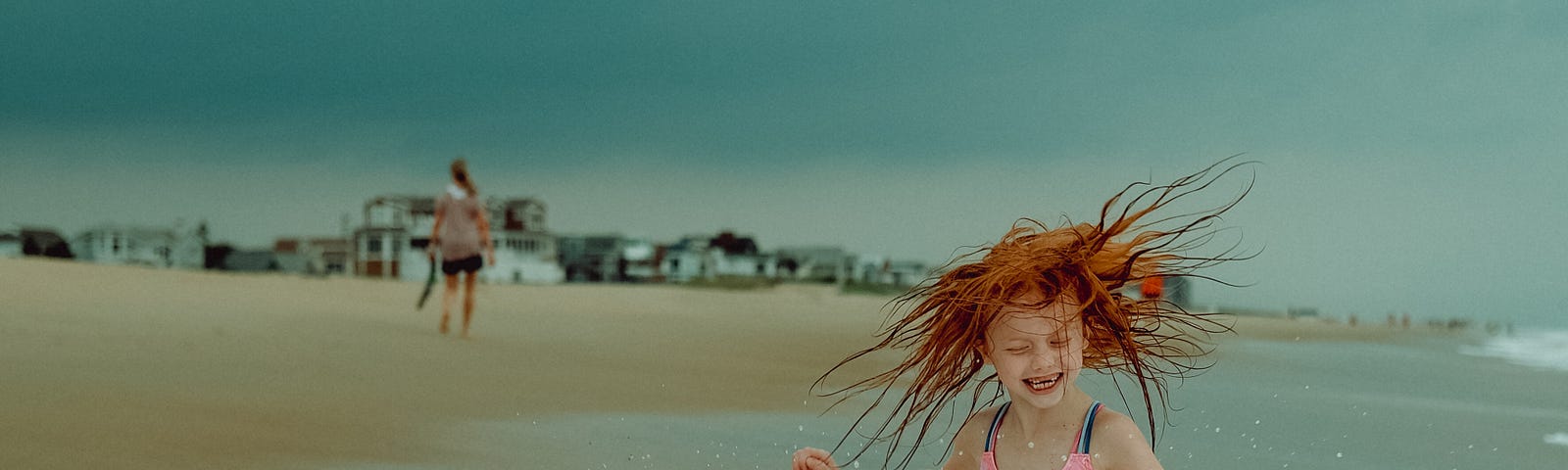 Red-headed girl cavorting in the surf at the beach.