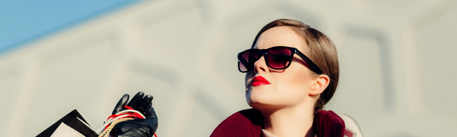 Lady wearing sunglasses and carrying lots of shopping bags.