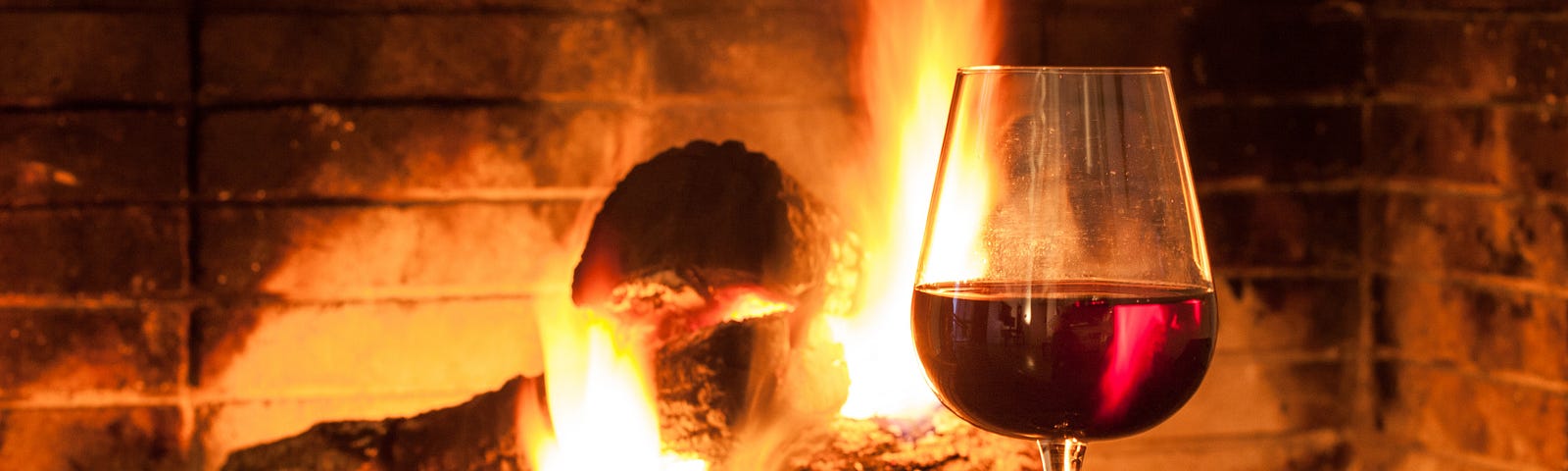 A wine glass near a log fire