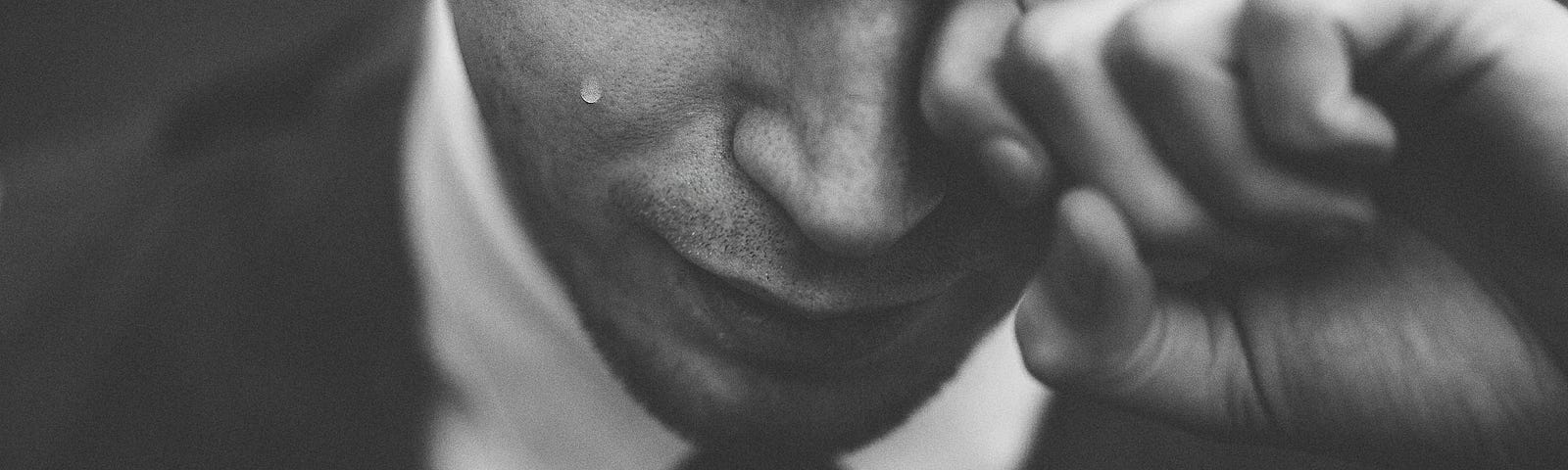 black and white photo of a man in a tie suit crying