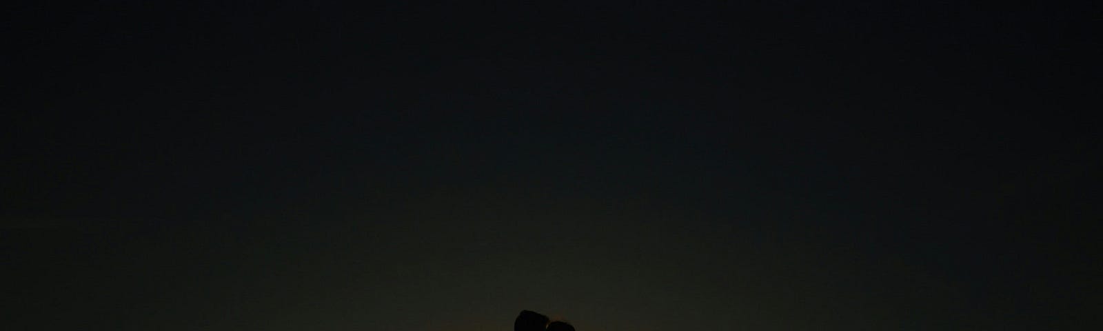 Two figures, silhouetted against the horizon, embrace in a tender embrace