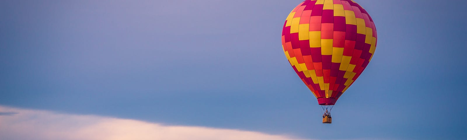 red, yellow and orange hot air balloon flying over trees