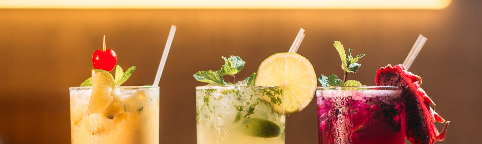 Three cocktails lined up on a bar