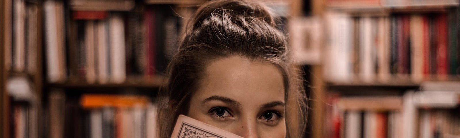 A stock photo of a young woman holding a record of Johann Strauss’ Die Fledermaus. Presumably, she is in a library as there is a bookshelf in the background.