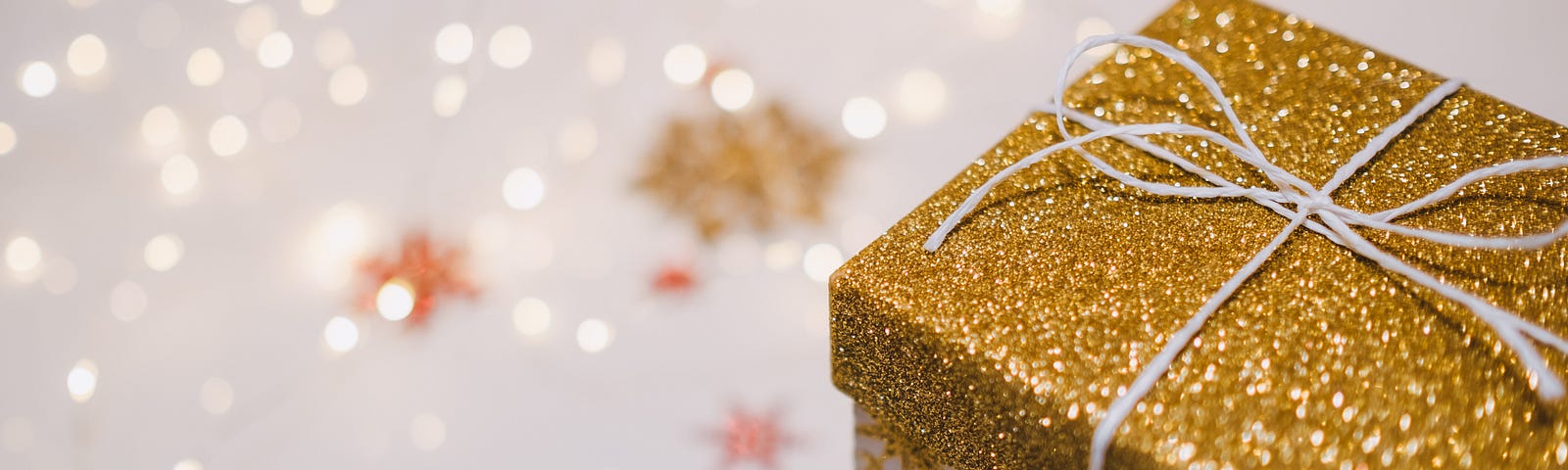 A present in a box wrapped in gold paper lying on a napkin with stars