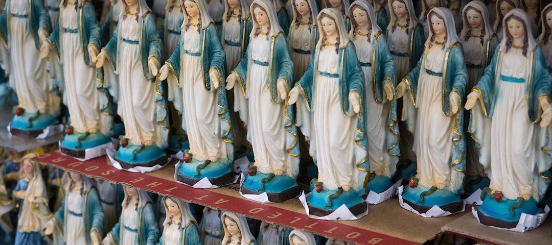 two shelves full of statues of the virgin mary