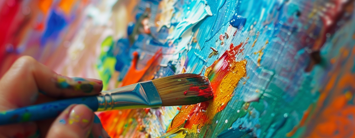 close up of a colorful canvas with a paintbrush being applied by hand