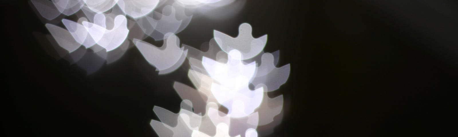 white angel cutouts blurred on a dark background
