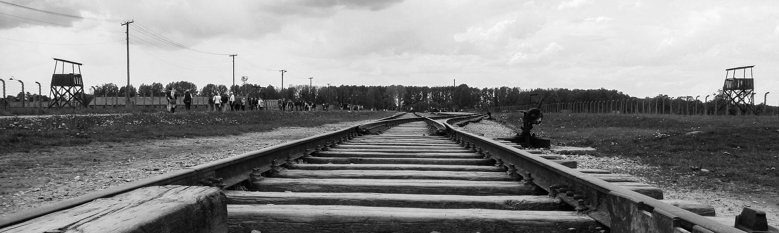 A black and white photo of the train tracks leading to a concentration camp.