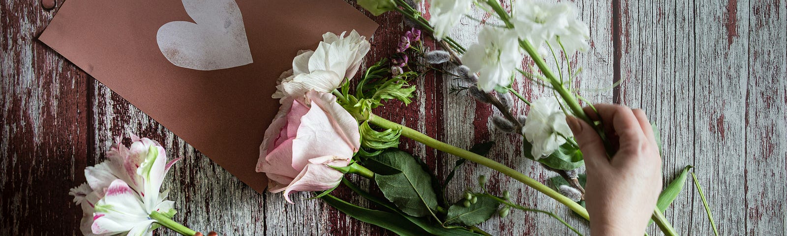 wooden table with cut fresh flowers being arranged by woman, mothers day 2024, mothers day calendar date, mothers day gift ideas, last minute mothers day gifts