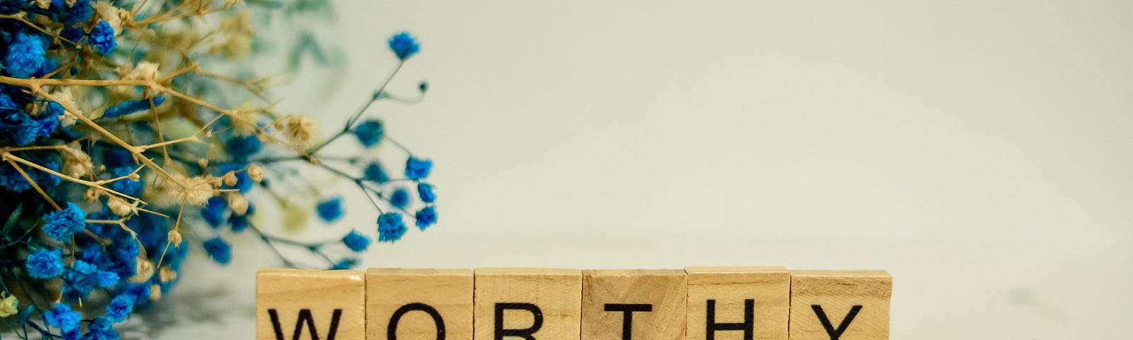 ‘Worthy’ spelled out in scrabble tiles, with some flowers in the background, because why not?
