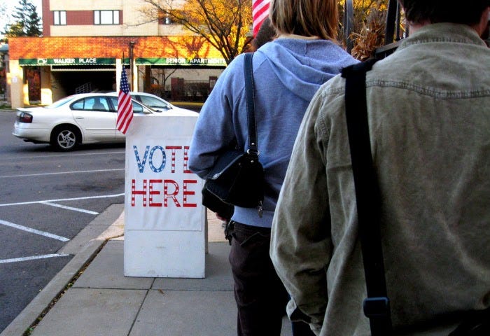 People standing in line on a sidewalk waiting to vote.