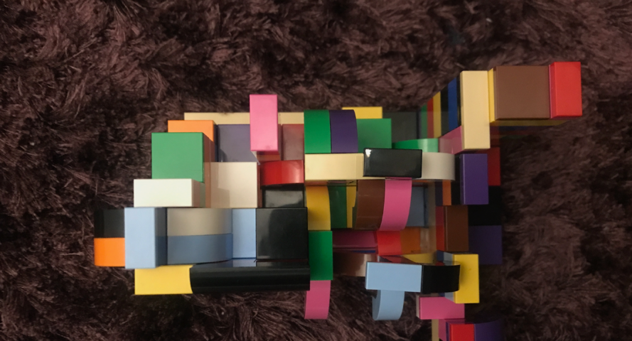 Arte em lego, com peças multicoloridas e multiformas, contra um fundo felpudo em tons de roxo.