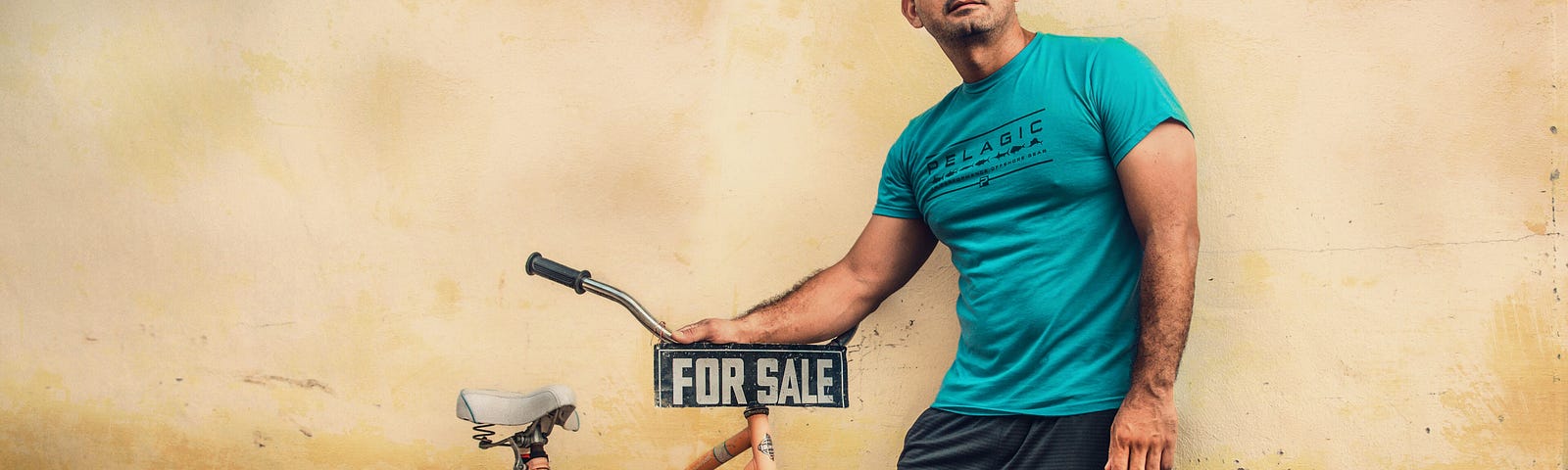 A man trying to sell a woman’s bicycle with “for sale” sign