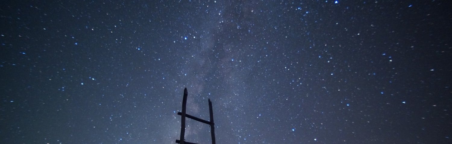 wooden ladder reaching up to starlit sky