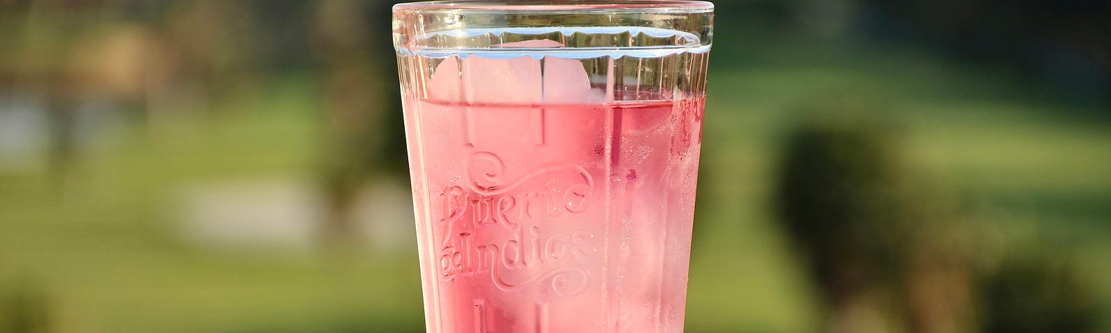 A refreshing glass of a pink drink with ice.