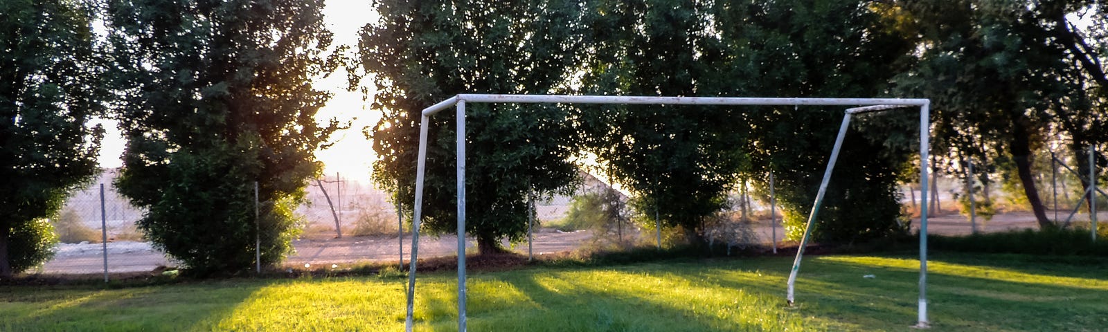 soccer goalpost standing in a grassy field with rays of sunlight