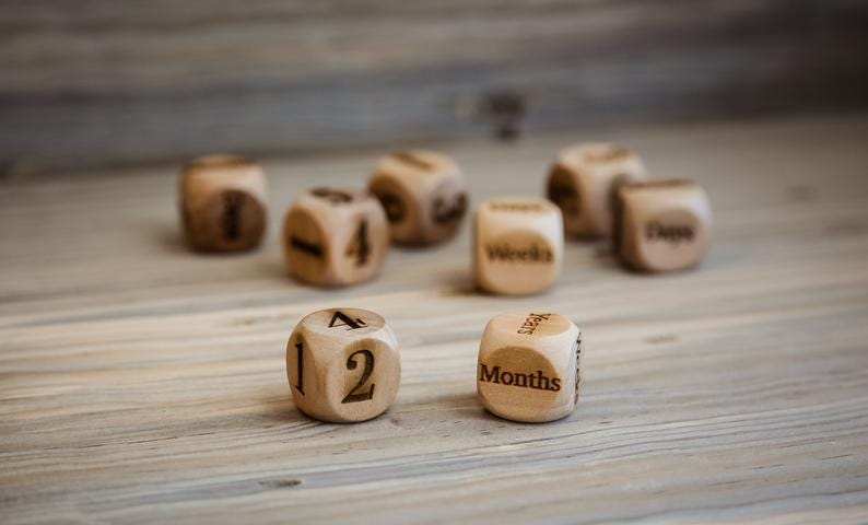 wood dice with numbers and the words “days”, “weeks”, “months”, and “years”
