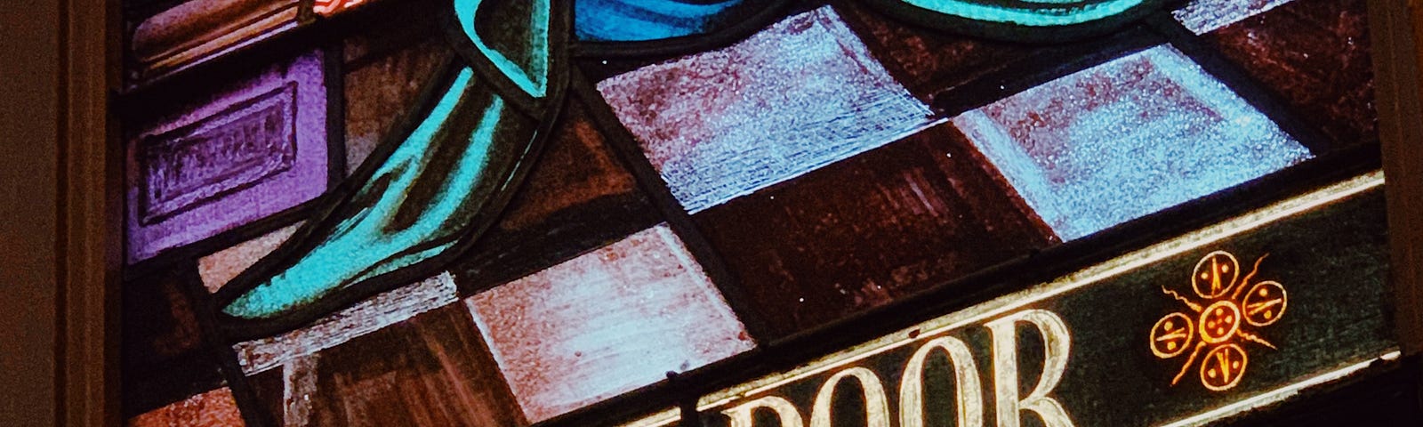 A stained glass church window; a depiction of Jesus Christ with the words ‘For The Poor’ inscribed below.