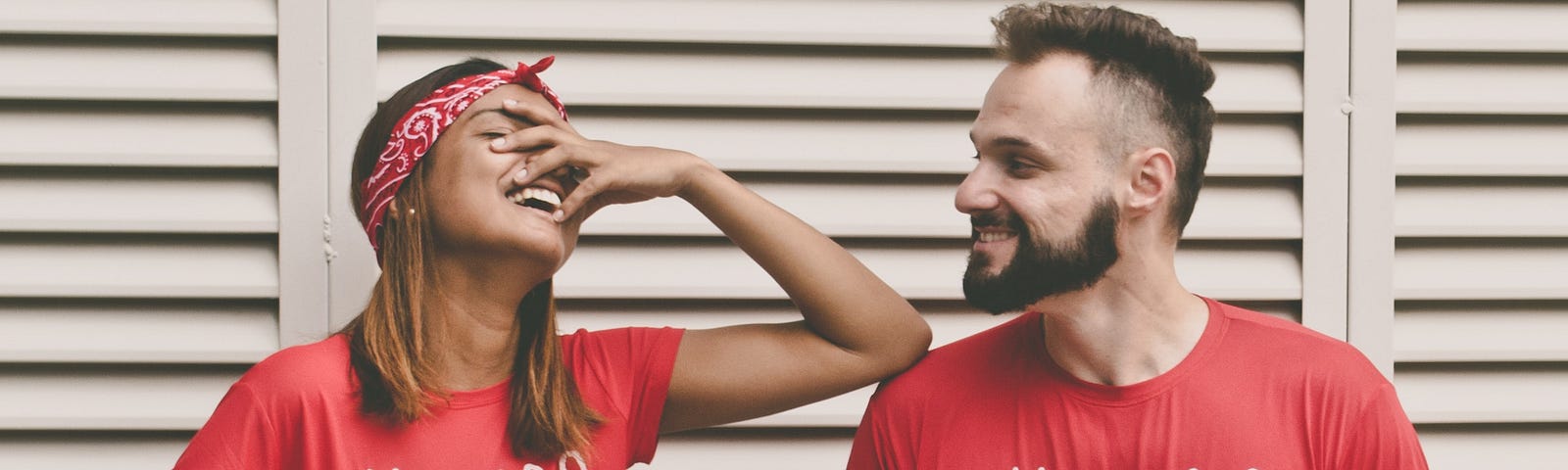 A woman in a red shirt labeled “thankful” grimaces at a man in a similar shirt, perhaps at a joke he cracked.