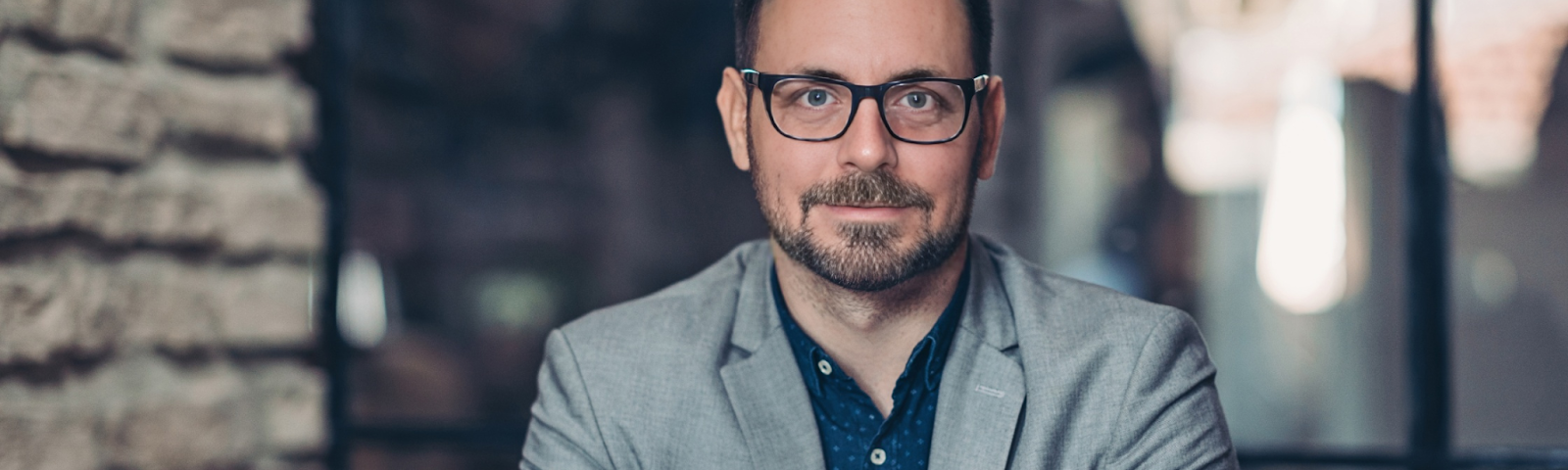 Photo of the author, a thoughtful entrepreneur in a suit jacket, sitting and internalizing lessons learned from a decade as a production manager in various industries. This reflective image captures the transition from a corporate 9-to-5 role to successful entrepreneurship, embodying themes of leadership, management innovation, and personal growth in the journey from a regular job to business ownership.