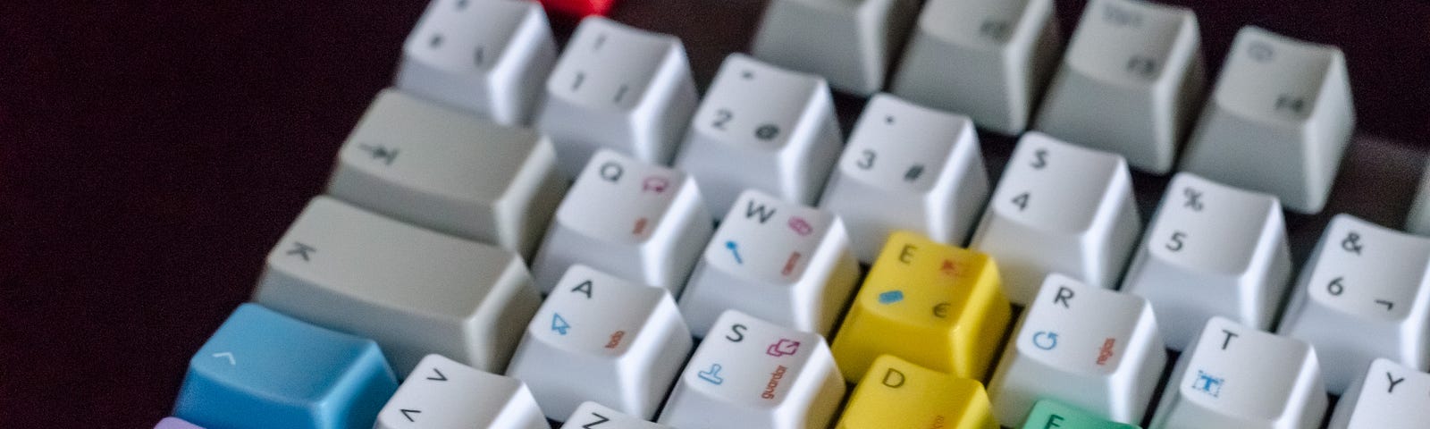 Computer keyboard with colourful keys sitting on a dark background.