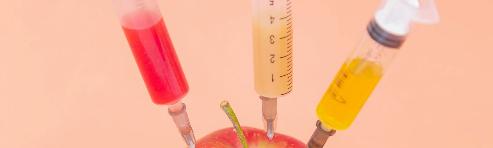 an apple being injected by three syringes