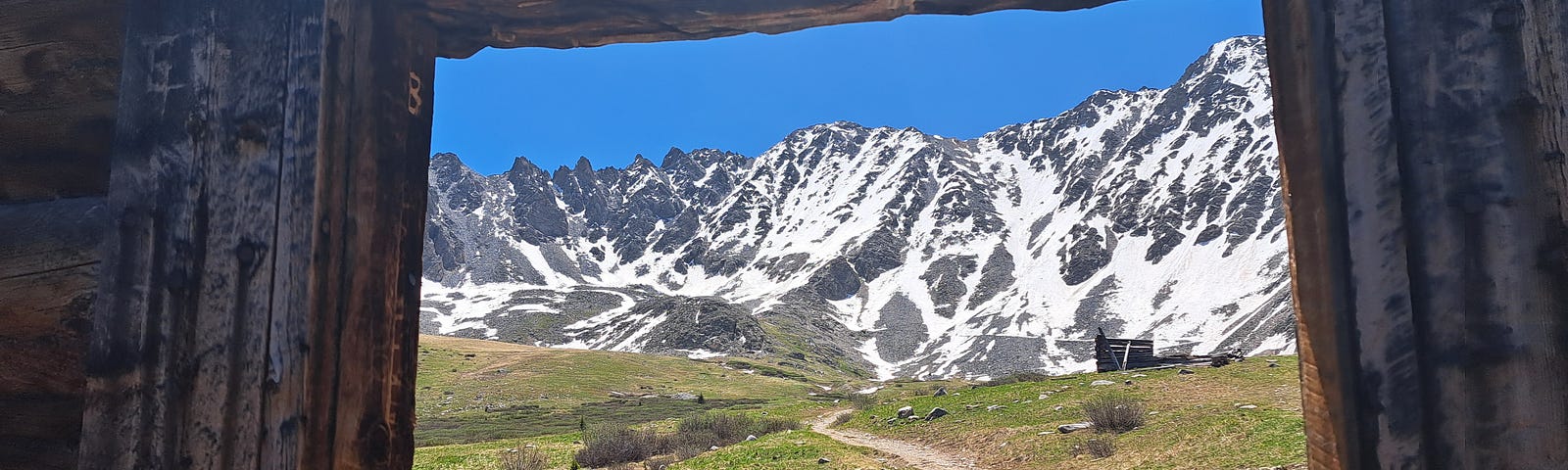 A rugged frame of an old window looking out to beautiful mountains.