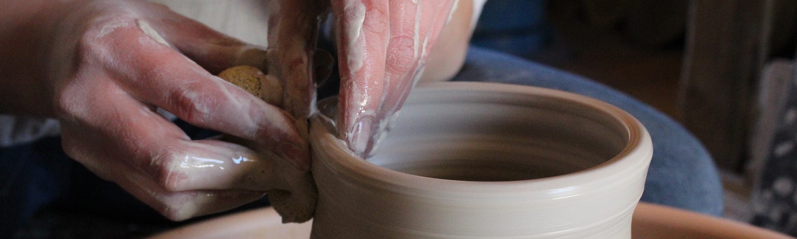 A potter shaping the top of a vase