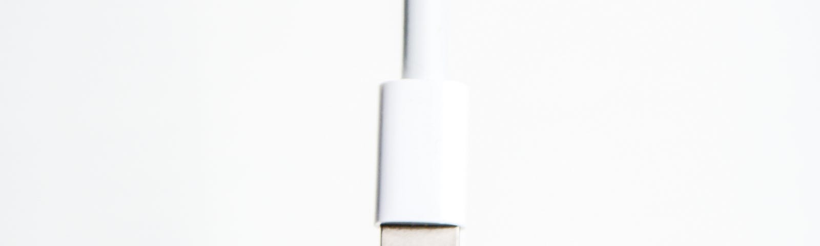 An Apple lightning cable on an off-white background.