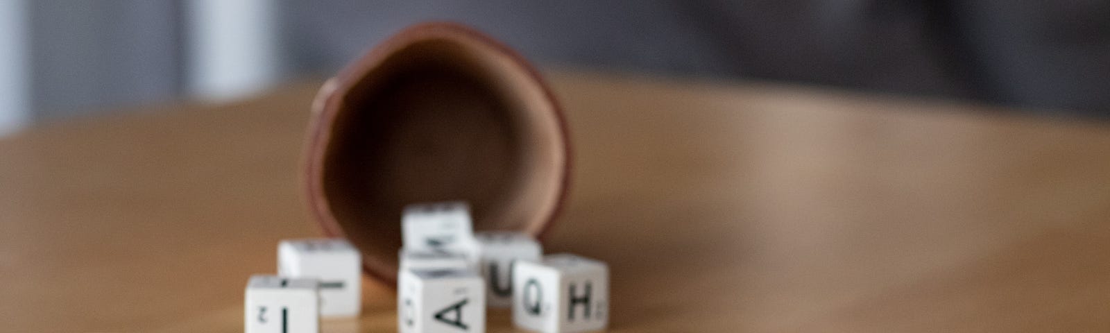 Scrabble pieces spill out of a small wooden cup, with six in the foreground spelling “DEMENZ.” Dementia is a general term for loss of memory, language, problem-solving, and other thinking abilities that are severe enough to interfere with daily life. Alzheimer’s is the most common dementia cause.