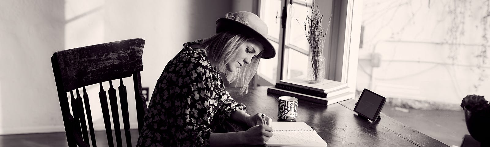 a black and white photo of a woman writing in her journal.