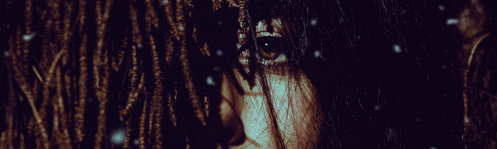 Ethnically ambiguous woman stares at camera. Hair and feathers obscure her face.