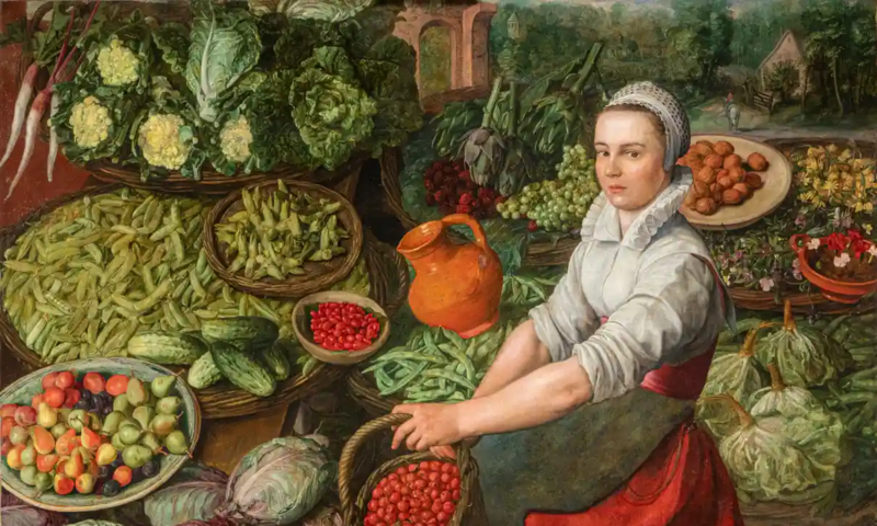 A painting of a young woman surrounded by an assortment of vegetables, fruits, and nuts in baskets. She has her hair tucked in a cap, a light colored shirt with a standing collar and her sleeves are rolled up to her elbows. A dark green apron covers the front of her red dress from the waist down. She is holding a basket of red fruit.