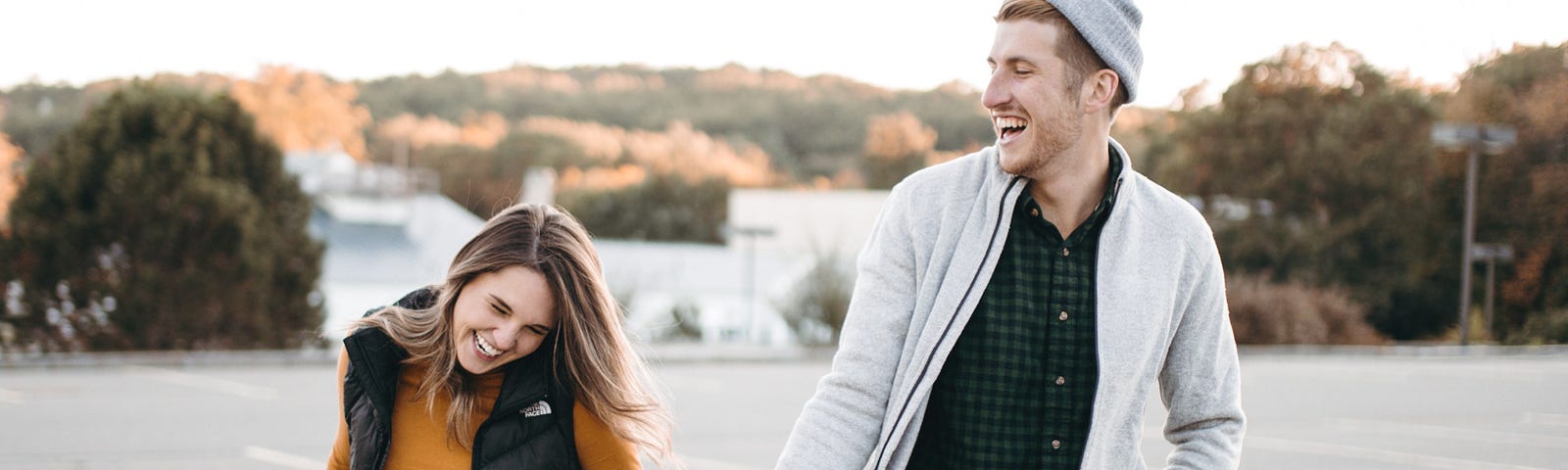 A young man and woman walking across a parking lot.