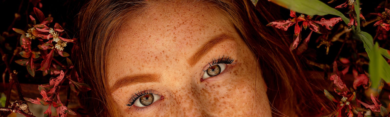 A beautiful girl with ginger hair, hazel eyes, and freckles lies in nature. She stares up and ponders humanity and the interconnection between all.