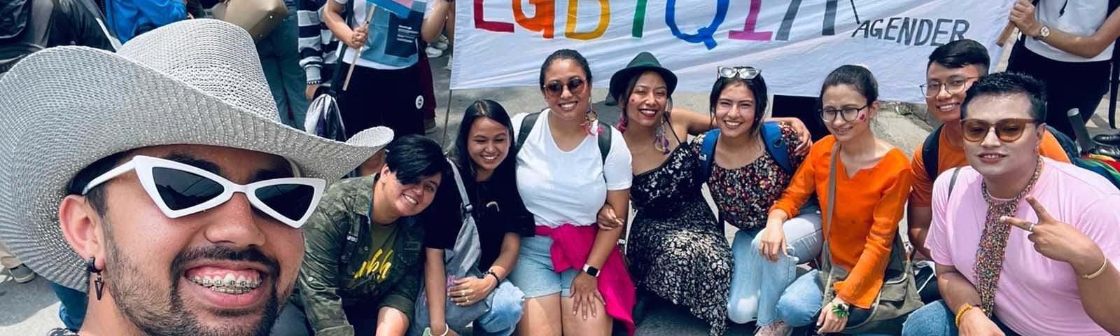 A picture of a number of people at the parade including my colleagues in front of a flag that says LGBTQIA where A stands for Asexual, Aromantic, and Agender.